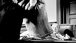 The history of distance education starts with the postal service; here a man empties a bag of letters on a desk.