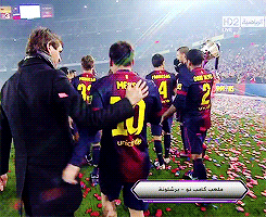 A coach rubbing a player's back and hugging him on the field