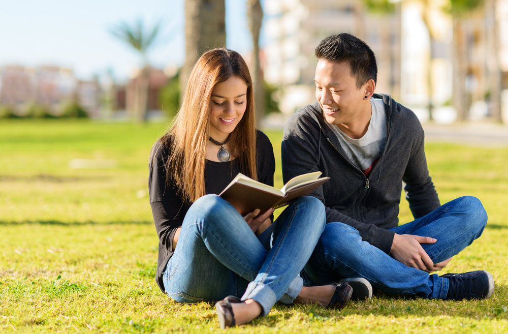 A girl holding a book and discussing it and her reading list with the boy sitting next to her