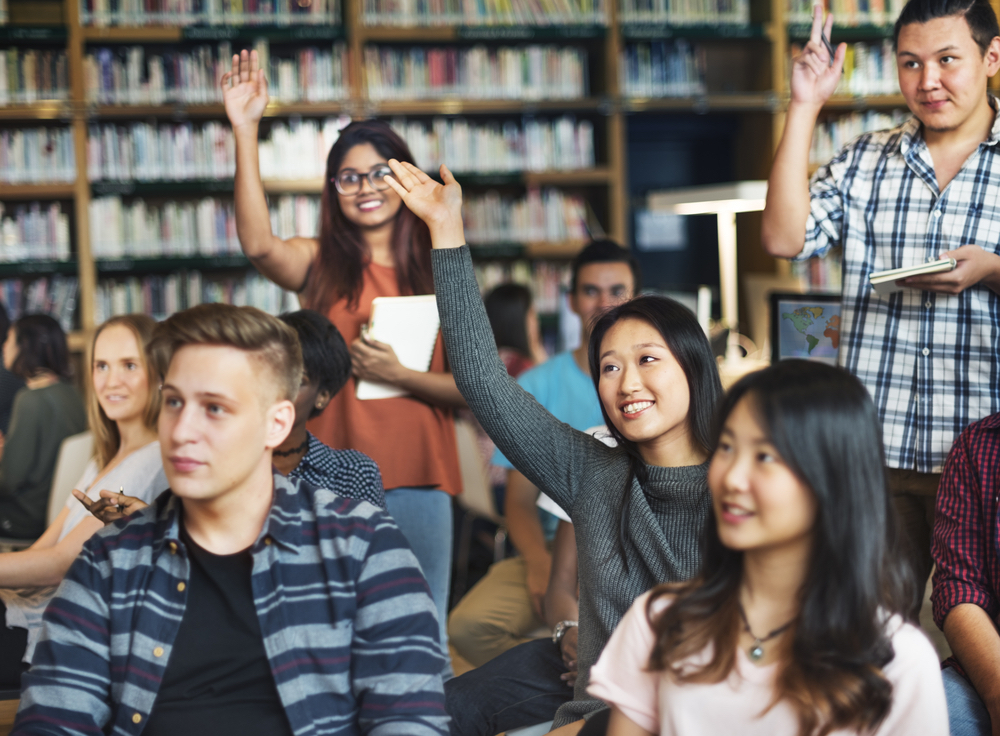 Students raise their hands in class