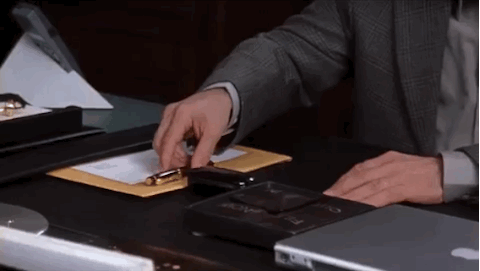 A man moving things around on his desk saying "But I'm pretty organized myself."