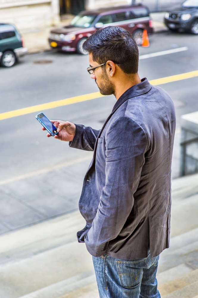 A man checks the safety apps on his phone before walking home.
