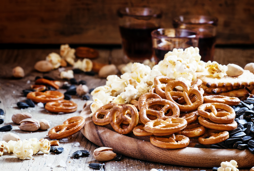 A plate of snacks that provide some essential nutrients: pretzels, popcorn, sunflower seeds, and pistachios.