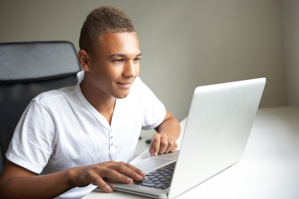 A boy searches the internet for foster youth scholarships.