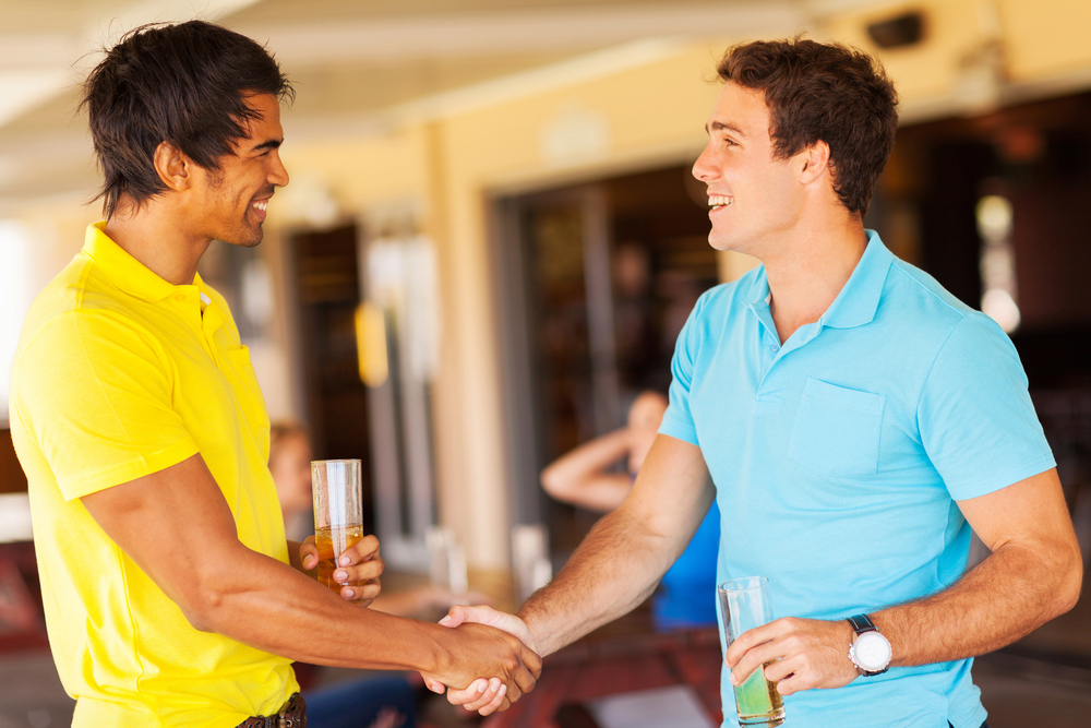 Two frat brothers greet each other at an event.