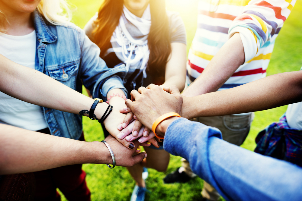 A group of students piles their hands together after they receive scholarships for American Indians.