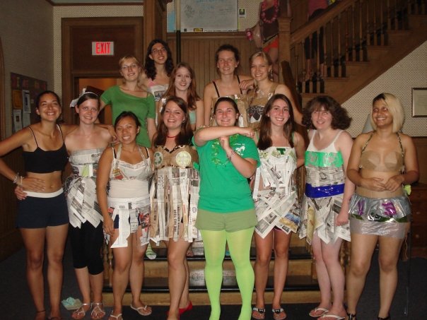 A group of female students in various costumes stand at the base of a staircase at a women's college.
