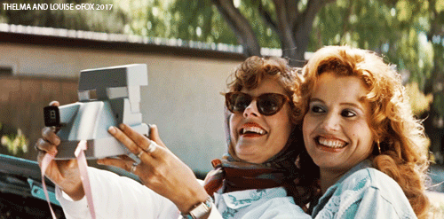 Thelma and Louise take a selfie with a Polaroid camera.